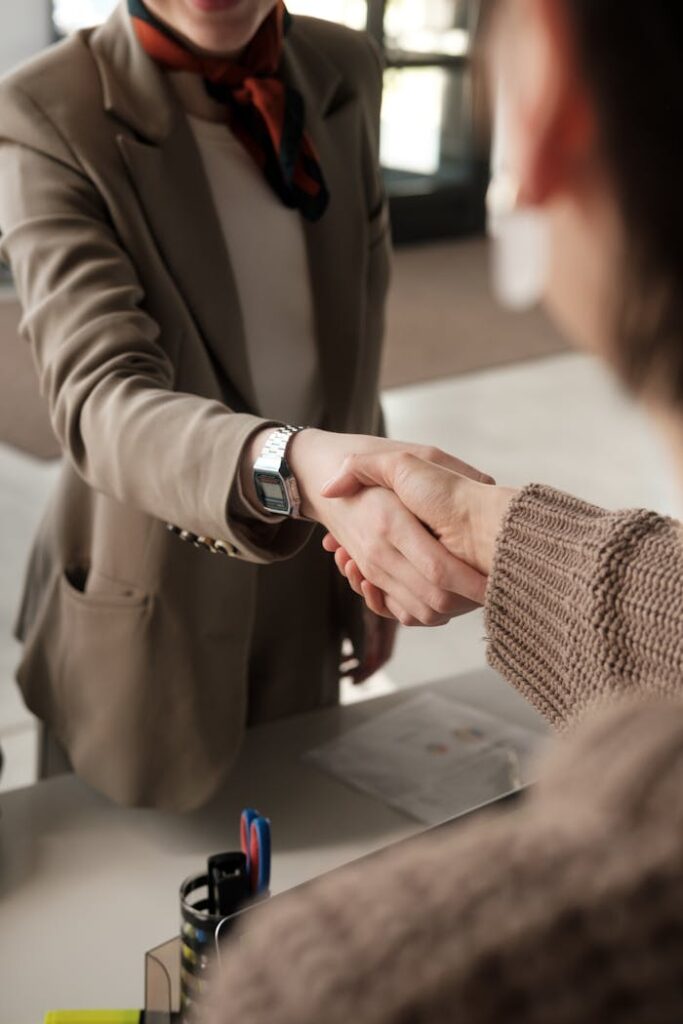 Two professionals shaking hands in an office, signifying a successful business agreement.